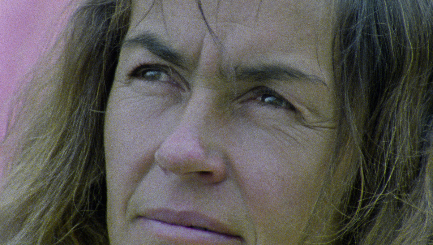 Zbliżenie na twarz kobiety. Kobieta ma lekko zmrużone oczy i rozpuszczone włosy.