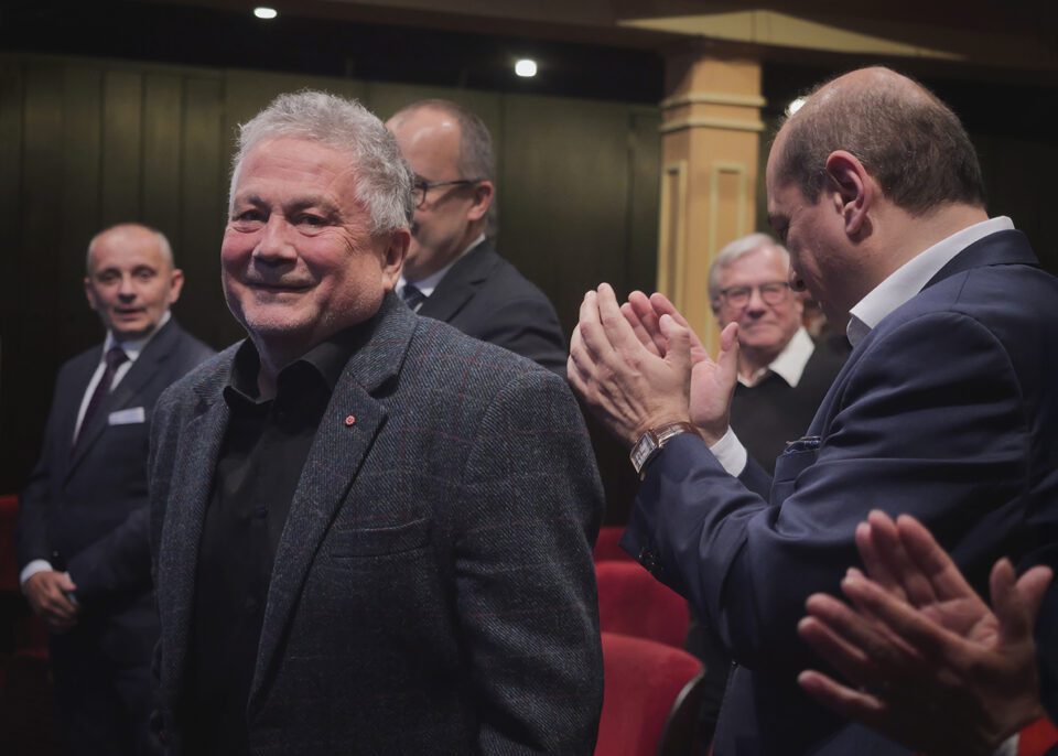 Zdjęcie zrobione na widowni teatralnej, w centrum kadru Andrzej Peciak; mężczyzna jest oklaskiwany przez ludzi dookoła niego.